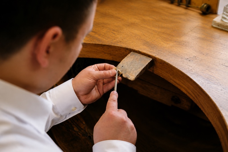 Goldschmied graviert einen Ring mit Saphir